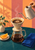A hand pours coffee from a gooseneck kettle into a paper-filter brewer above a glass carafe on a teal tabletop.