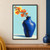 Cobalt-blue vase holding branching coral-orange blossoms against a pale-aqua background with a yellow oval accent.; frame shown for styling only
