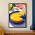 Glossy lemon tart on a cobalt plate with a slice lifted above it, beside a lemon, leaves, coral cloth, and a glass of water.; frame shown for styling only