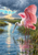 Pink roseate spoonbill with raised wings and a droplet-tipped bill standing in reflective marsh water beneath clearing storm clouds.