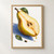 A ripe pear cut lengthwise with seeds showing and an amber drop falling from its tip, above a blue shadow on a pale background.; frame shown for styling only