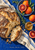 Overhead still life of rustic bread, blood oranges, honey, rosemary and blue-striped linen with the title Sunday Market Table.