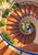 Terracotta spiral staircase with cobalt-blue railings winding above a planted court and small fountain.