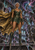 Silver-haired fantasy elf warrior in green-and-gold armor and a flowing gold cape before ruined arches and a swirling cosmic sky.