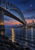 Large steel arch bridge over a dark river at blue hour, with an illuminated ferry, gold reflections, distant city, and rocky bank.