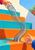 Reflective silver-blue spiral spring toy extending between two hands over bright turquoise and orange steps.