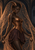 Fantasy woman in a copper-gold bodice holding two vessels beneath a glittering veil in a stone arch.