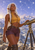 Pointed-eared, white-haired woman beside a brass telescope overlooking snowy mountains beneath a lavender sky with stars and connecting lines.