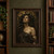 Close portrait of Medusa with dark snakes framing her head and shoulders, wearing a dark draped garment against a bronze-brown background.; frame shown for styling only