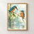 Two turquoise and rust-orange kingfishers perch on a diagonal reed above pale water; the larger bird holds a small fish.; frame shown for styling only
