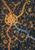 Overhead view of an imagined city at night with a glowing circular plaza, winding amber, gold and blue routes, rooftops and dark waterways.
