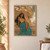 Seated woman in turquoise and gold before a monumental closed-eyed sphinx sculpture in a desert scene.; frame shown for styling only