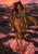 Horned woman in a green top and gold wrap walks across glowing fissured volcanic terrain at sunset.