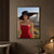 Fashion portrait of a woman in a red strapless dress holding a broad black hat in a rocky, grassy landscape.; frame shown for styling only