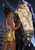 A woman in lavender and gold touches a large faceted crystal containing a glowing tree beneath a small moon and stars.
