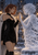 Two women meet palms in a snowy gothic courtyard, one in a dark dress with auburn hair and the other pale and frost-covered.