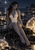 Gray-toned pointed-eared woman with long dark hair seated on a rocky shore among glowing golden spheres beneath a moonlit sky.