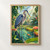 Blue-gray heron and goldfish in a lily-filled greenhouse pond surrounded by tropical foliage.; frame shown for styling only