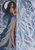 Dark-haired woman in a blue gown faces a luminous female-like double across an icy divider beneath a moon and stars.