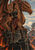 Woman warrior with a spear stands before a huge orange dragon on basalt columns above a lava-lit landscape.