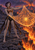 Pointed-eared woman in bronze-and-black fantasy attire holds a glowing orange spider web above volcanic rock and a lava fall.