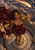 Curly-haired woman in a burgundy gown and flowing gold-lined cape reaching from a circular terrace beneath a comet over a castle city.