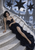 Dark-haired woman in a long black gown on pale curved steps beneath black star shapes, with distant ruins.