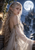 Silver-haired pointed-eared woman in a white gown with a full moon, distant castle, mountains, and waterfall behind her.