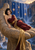 Dark-haired woman in a burgundy gown reclines on a rock ledge before a star-dotted waterfall and warm sunset sky.