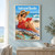 Adult woman in a red dress reading a red book on a striped beach blanket, holding her straw hat with waves and gulls behind her.; frame shown for styling only