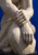 Pale stone hands folded over a bent knee against a saturated ultramarine background.