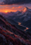 A rose-gold-lit mountain peak rises above a dark alpine valley as a reflective river winds toward a low sunset beneath storm clouds.