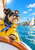 A black-and-tan schnauzer-type dog in a yellow slicker and striped scarf stands at a wooden boat bow overlooking a bright harbor and sailboats.