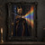 A regal woman wearing a gold horned headpiece stands in a dark gothic interior amid a beam of rainbow light.; frame shown for styling only