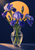 Three purple irises and a closed bud in a reflective clear glass vase against a deep indigo background with an apricot disc.