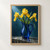 Three yellow irises and long green leaves in a glossy cobalt-blue glass pitcher on a wet stone ledge.; frame shown for styling only