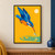 A cobalt-blue and orange kingfisher dives toward a small silver fish above turquoise ripples on a marigold background beneath a pale sun.; frame shown for styling only