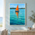 Small sailboat with a red-orange triangular sail and dark hull floats on turquoise water, casting a long orange reflection before a wooded shoreline.; frame shown for styling only