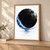 A textured black disc is crossed and partly encircled by a vivid blue brushstroke, with a pale blue reflection and small title lettering below.; frame shown for styling only