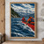 Two paddlers in red-orange jackets crossing choppy blue water in a red canoe, with evergreen shore and snowy mountains behind them.; frame shown for styling only
