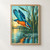 Blue-and-orange kingfisher diving toward a ringed ripple at dawn, with reeds and golden water reflections.; frame shown for styling only