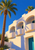 White resort façade with curved balcony fronts and turquoise doors, framed by a tall palm against cobalt sky.