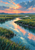 Winding reflective channel through a marsh with two distant white birds beneath a coral-and-gold dawn sky.