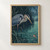 A blue-gray heron leans toward a small red-orange fish surfacing among rain-streaked water and dark reeds.; frame shown for styling only