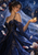 An adult bride in a dark blue gown and translucent veil looks at a glowing moth on her open hand beneath a crescent moon.