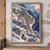 Snow leopard stepping down snowy rock ledges above a deep blue alpine ravine.; frame shown for styling only