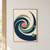 Midnight-blue and sea-glass-green curved bands spiral around a coral disk on a warm sand background.; frame shown for styling only