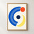 Minimalist poster with a broad cobalt C-shaped arc, cream curved lines, vermilion circle, pale yellow crescent, and navy dot on warm off-white.; frame shown for styling only