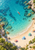 Aerial view of a coral kayak and two swimmers in turquoise water beside a curved sandy beach with striped parasols.