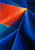 Blue and teal geometric planes converge around a vivid vermilion wedge, with small pale title lettering near the bottom.